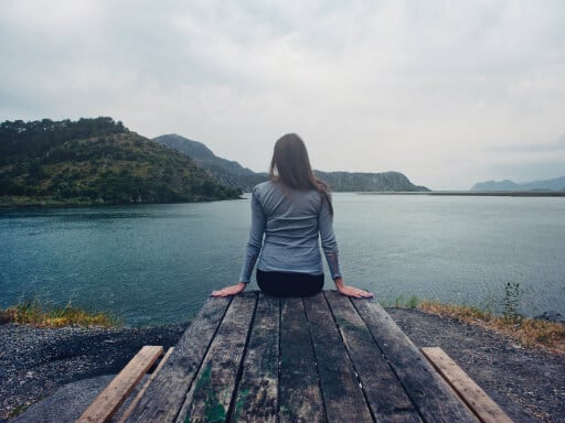 lady sitting on a dock looking over a lake