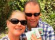 A man and a woman holding green cards