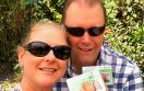 A man and a woman holding green cards