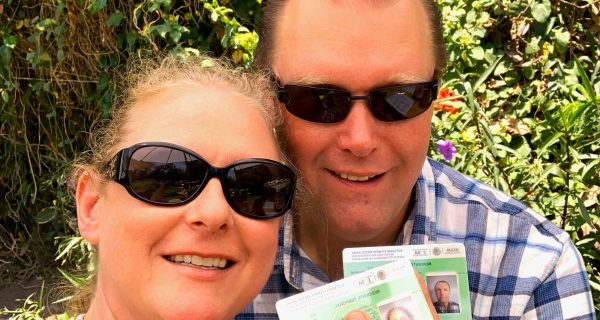 A man and a woman holding green cards