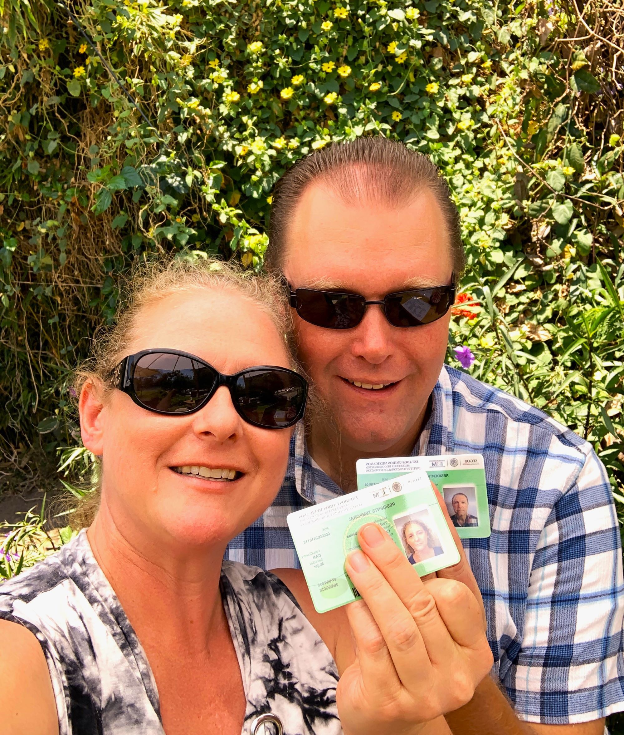 A man and a woman holding green cards