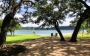 two chairs overlooking a lake underneath shade trees