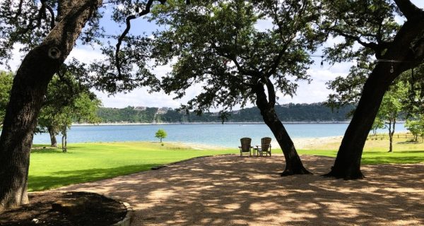 two chairs overlooking a lake underneath shade trees